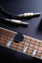 Guitar frets with strings and mediator, jack cable on dark Royalty Free Stock Photo