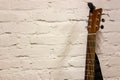 Guitar headstock and neck against white background. Musical instruments stands leaning on brick wall with empty copy space to add