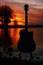 Guitar by the lake at sunset time Royalty Free Stock Photo