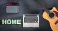 Guitar, laptop, speaker and word Home on a black background, top view. Royalty Free Stock Photo