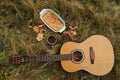 Guitar lying on an autumn green and yellow grass next to a cup of tea and a pie