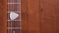 Guitar pick on wooden guitar neck on the frets of the guitar on wooden background Royalty Free Stock Photo
