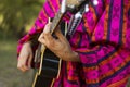 Guitar that is played by the hands of a man with colorful clothe Royalty Free Stock Photo