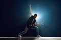 Guitar player engaging with music and shows Rock-n-Roll gesture on stage with backlights against black background with Royalty Free Stock Photo