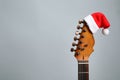 Guitar with Santa hat on grey background. Christmas music