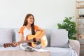 Guitar and singer concept, Young asian woman sitting on couch to playing music with acoustic guitar Royalty Free Stock Photo