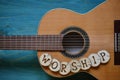 Guitar on teal wood with the word: WORSHIP