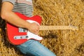 Guitar telecaster in red with a wooden stamp in the hand of a musician background of straw on a sunny summer day Royalty Free Stock Photo