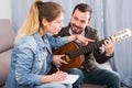 Guitar tutor helping client learn instrument