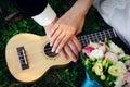 Guitar, wedding bouquet and hands of the newlyweds, close-up. Ukulele, hands of the bride and groom with wedding rings Royalty Free Stock Photo