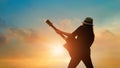 Guitarist playing acoustic guitar on the colorful cloudscape sunset