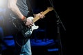 The guitarist plays the electric guitar. Guitar neck close-up on a concert of rock music in the hands of a musician.