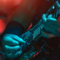 The guitarist plays the guitar in the spotlight. Hands of a Guitar player playing the guitar. Low key Royalty Free Stock Photo