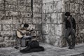 A guitarist plays in the street while people listen.