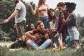 Guitarist trying his best. Group of people have picnic on the beach. Friends have fun at weekend time