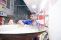 Man curdling milk in a huge pan to make indian sweets