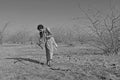 Gujarat: Indian girl chopping down wood in rural desert area