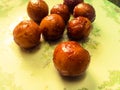 Gulab Jamun balls with sugar syrup placed in a white plate.