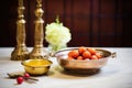 gulab jamun in brass bowl beside a diya lamp