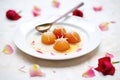 gulab jamun on white plate with rose petals Royalty Free Stock Photo