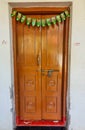 Stock photo of old brown color painted door decorated with artificial mango leaf toran or