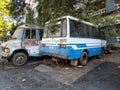 Stock photo of abandoned broken, damaged white and blue color two vans, left in the scrap yard for recycling, g.