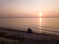 The Gulf of Riga, the Curonian Spit can be seen in the distance. Sunset, quiet summer evening. People look at the sunset Photo fro