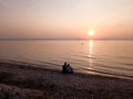 The Gulf of Riga, the Curonian Spit can be seen in the distance. Sunset, quiet summer evening. People look at the sunset Photo fro