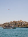 Gulf between Valletta and Vittoriosa with passing boat with tourists and international plane in the sky