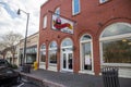 Gumbeauxâs Cajun CafÃ© in a red brick building with shops and restaurants along the street, parked cars, tall curved light posts