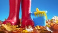 Gumboots on golden leaves with sandbox toys