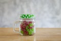 Gummy candies in a glass jar on wooden table.