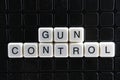 Gun control text word crossword. Alphabet letter blocks game texture background. White alphabetical letters on black