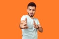 Gun gesture. Portrait of dangerous young brunette man pointing with finger pistols at camera. isolated on orange background