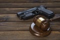 A gun and a hammer judge on the background of a wood texture table.