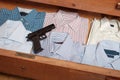 Gun hidden in drawer full of shirt at home Royalty Free Stock Photo