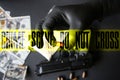Gun lying on the table. Man in black gloves holding bullets. Illegal drug selling. Crime scene do not cross tape. Dollars