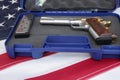 gun or pistol inlaid with wood and gold and bullet holder in a blue box on a american flag background. weapon concept. protection