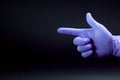 A gun sign by right man hand in a purple medical glove on a black background Royalty Free Stock Photo