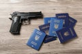 Gun with Ukrainian passports on wooden background