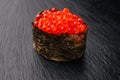 Gunkan ikura with caviar on a black