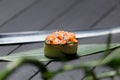 Gunkan Sake Green sushi on bamboo leaf near Japanese knife with green plant on foreground.