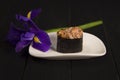 Gunkan sushi with salmon and Tobico caviar in nori seaweed on white plate with iris flower near Royalty Free Stock Photo