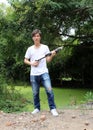 The gunner man holding long gun in hands and turned left sideways with white shirt and denim jean. Royalty Free Stock Photo