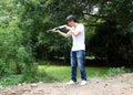 The gunner man standing long gun aiming right sideways with white shirt and denim jean. Royalty Free Stock Photo