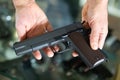 Gunsmith shop assistant demonstrates black pistol in hands
