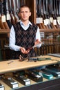 Gunsmith shop assistant demonstrates hunting knife in hands