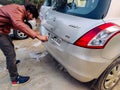 Man using a riveting locking tool to affix a tamper proof HSRP high security registeration plate to a maruti swift car