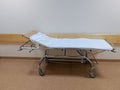 A Gurney bed covered in a white sheet or a stretcher on casters for transporting bedridden patients in the hospital corridor