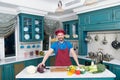 Guy in apron and hat in the kitchen made salad for vegans with lettuce and zucchini. Handsome man at home kitchen concept
